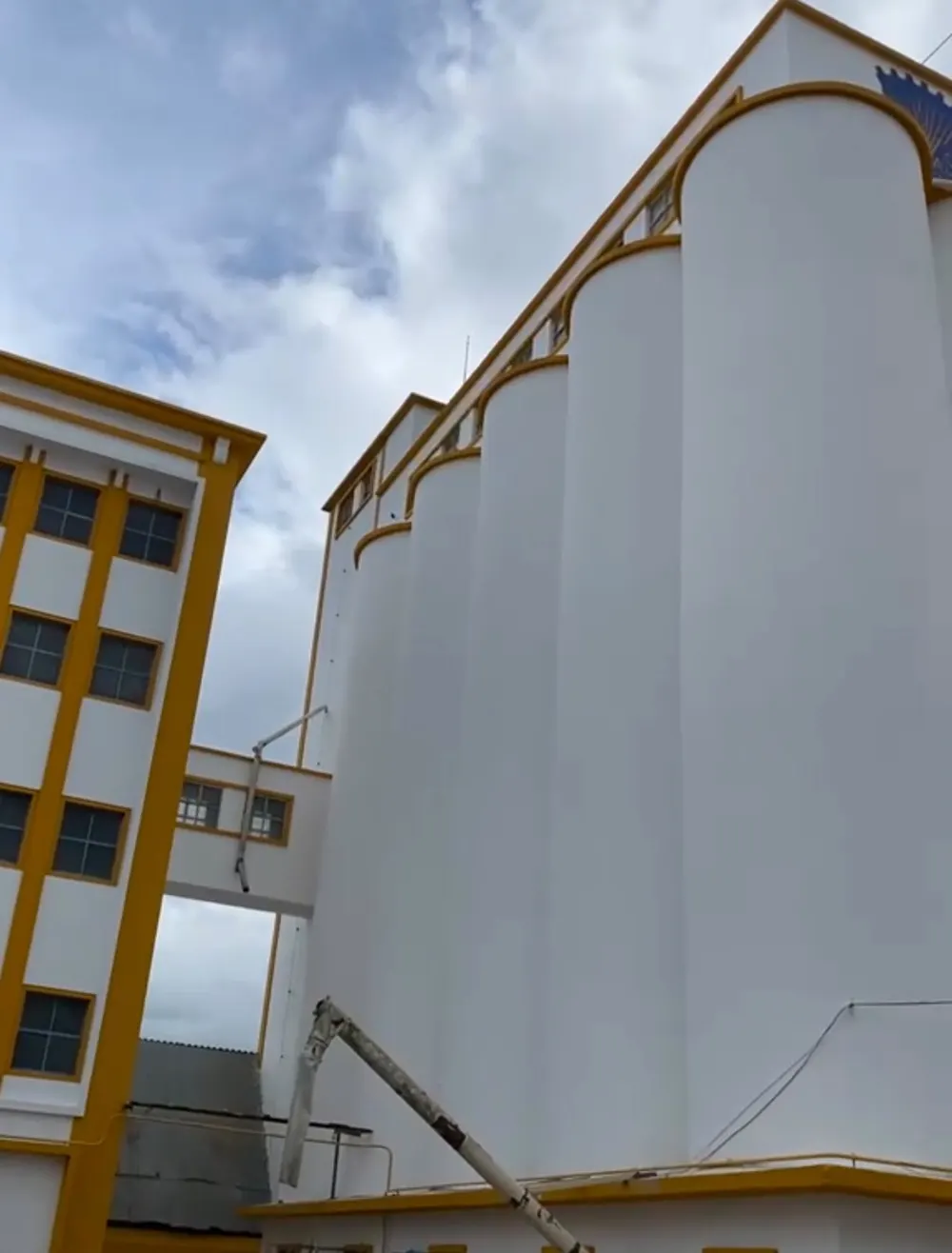Silos industriais pintados de branco com detalhes amarelos