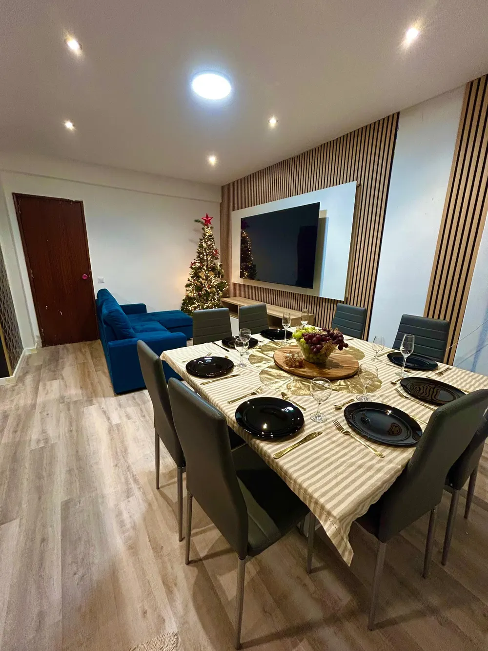Sala de jantar remodelada com painel de madeira e sofá azul