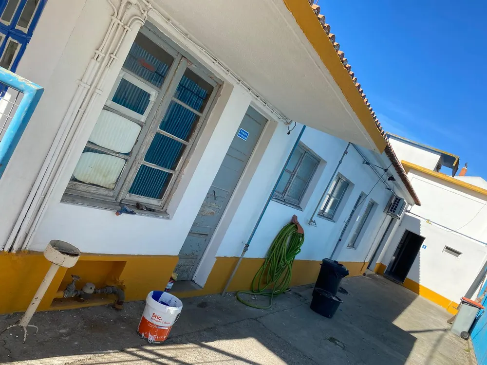 Moradia em pintura, com caixilhos azuis e base amarela